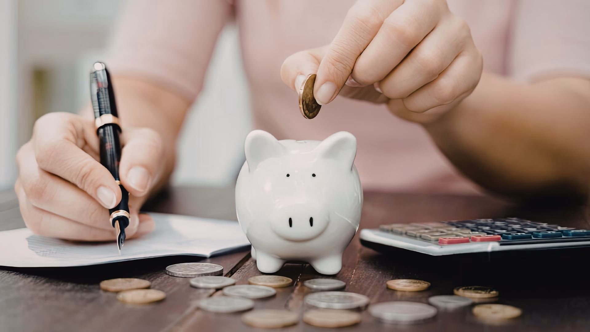A Person Putting a coin into a piggy bank.