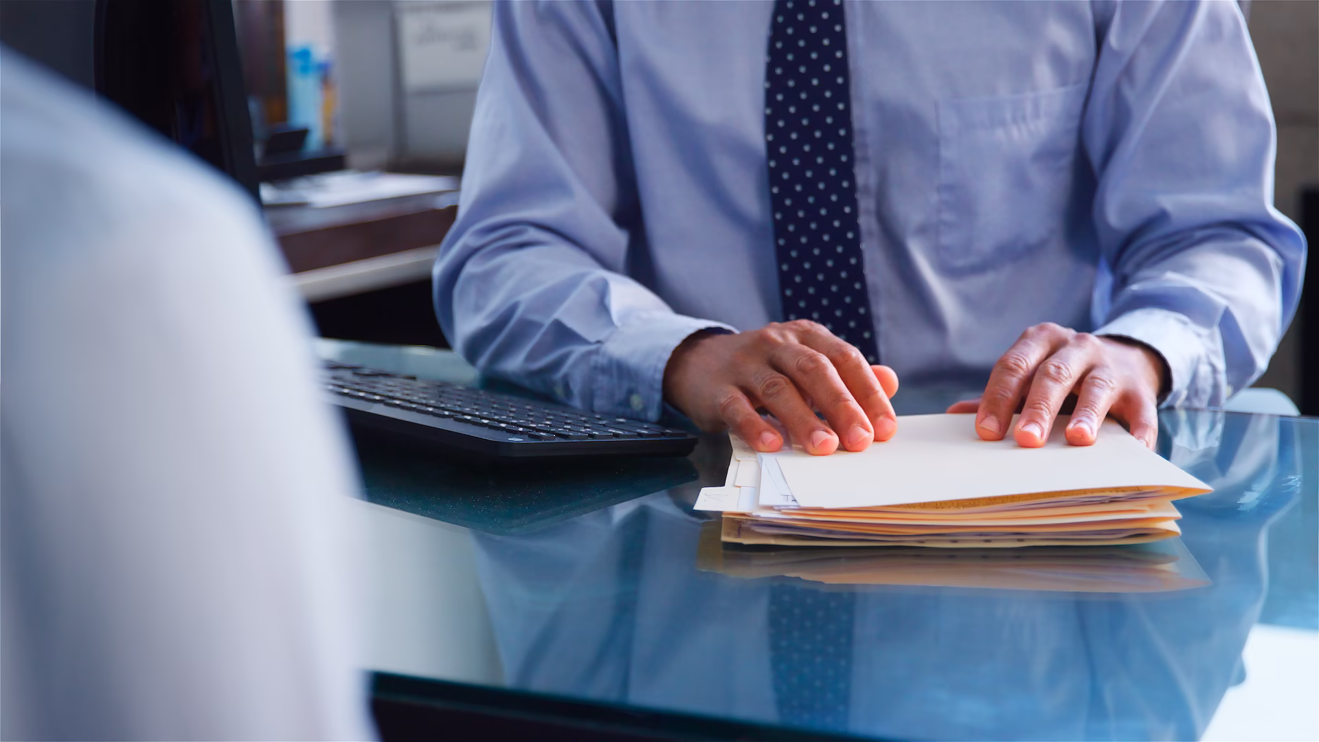 close-up-of-businessman-behind-desk-holding-files-2026-01-09-11-04-43-utc Close up of business behind desk holding files